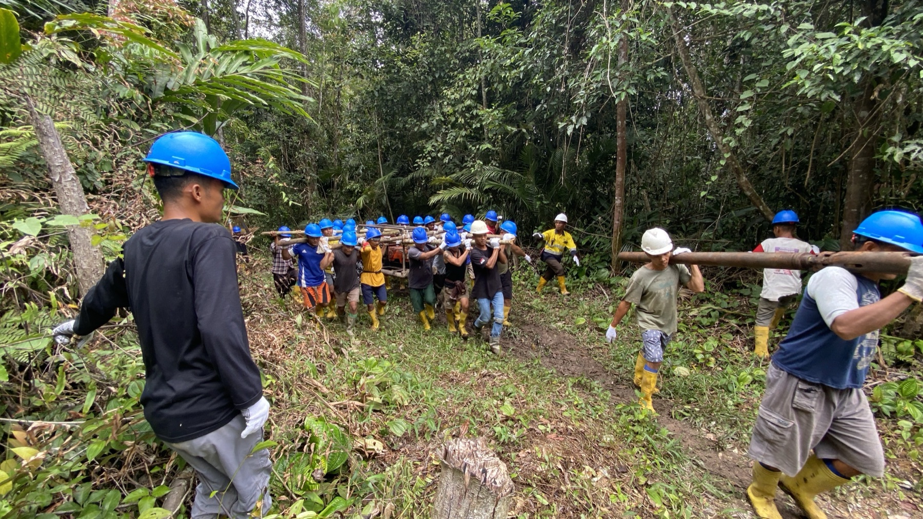 Drilling crew carrying rods into a jungle site in Timor-Leste